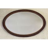 An oval mirror with inlaid wood surround. Approx 77cm wide.