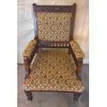 A Victorian decoratively carved nursing chair in mahogany with floral tapestry style upholstery.