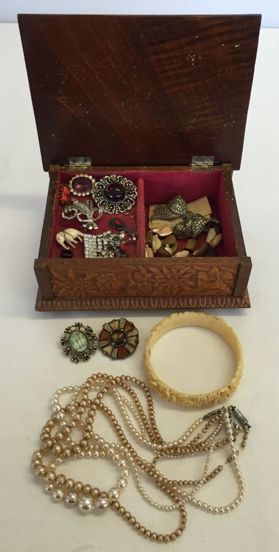 A small wooden carved musical jewellery box containing a quantity of costume jewellery to include