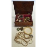 A small wooden carved musical jewellery box containing a quantity of costume jewellery to include