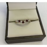 Ladies 'Wishbone' design dress ring set with 3 garnets and 4 cubic zirconias in hallmarked 9ct gold.