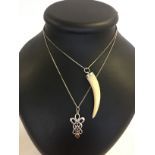 2 pendant necklaces on silver chains, one is a mounted animals tooth and the other a Celtic design