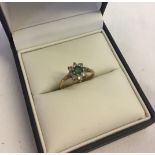 Ladies 9ct dress ring with central emerald surrounded by clear stones. Size O, total weight 1.7g.