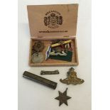 A box of military medals, badges and buttons with a brass gun oiling tool.