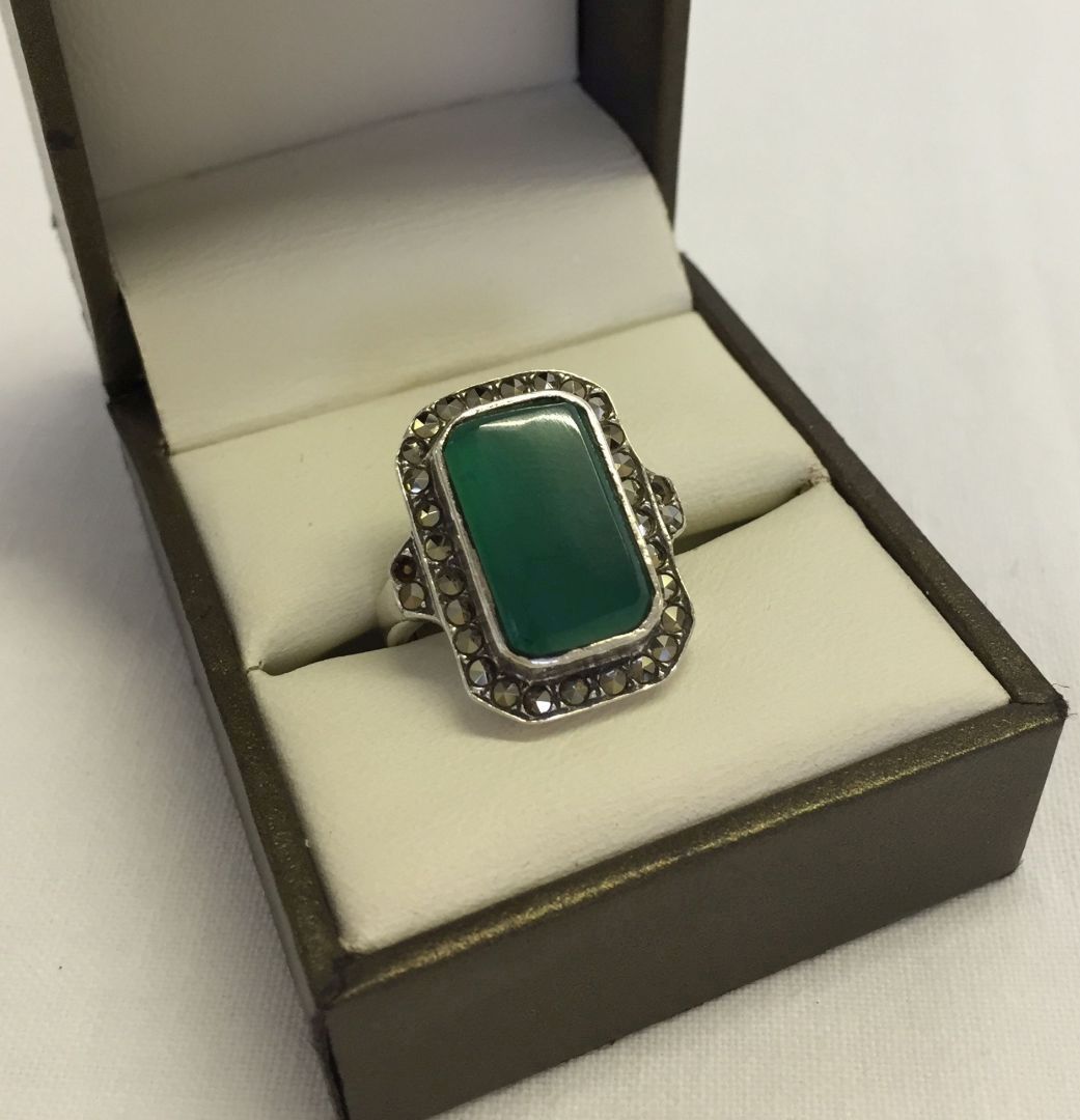 A 925 silver and marcasite ring set with a large green stone. Size M. 1 small piece dislodged on