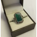 A 925 silver and marcasite ring set with a large green stone. Size M. 1 small piece dislodged on