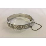 Heavy engraved hallmarked silver hinged bracelet with safety chain. Weight approx 37.7g.