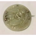 A large round Jade brooch, ornately carved with bird and flower decoration.