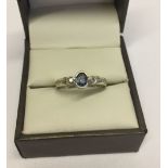 Modern design dress ring set with an oval sapphire and 2 small diamonds. Hallmarked 9ct gold, size