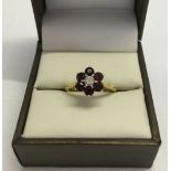 A boxed 18ct gold diamond and garnet cluster ring. Central diamond (approx .15ct) surrounded by 6