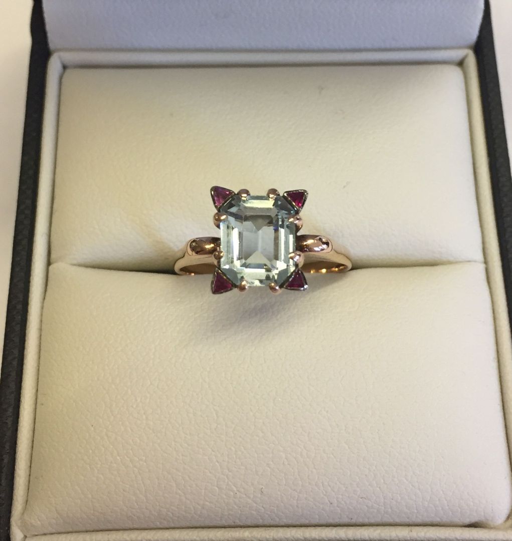 A c1930s 14ct rose gold ring set with baguette cut blue topaz with 4 triangular rubies, one at