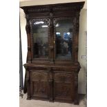 A large late 19th century dark oak ornately carved bookcase, possibly Flemish, with key. Approx