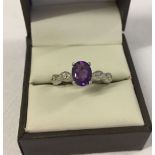 A 925 silver dress ring set with a central amethyst flanked by white topaz. Size R.