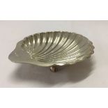 A silver platter in the shape of a clam shell on ball shaped feet. Hallmarked Sheffield 1910/11.