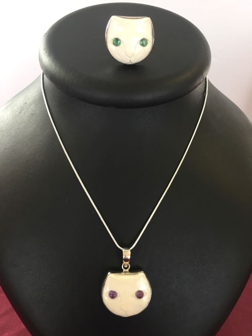 A carved cat face pendant with amethyst eyes set in 925 silver on a rope chain together with a