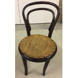 A childs dark wood bentwood chair with wooden seat.