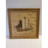 A wooden picture of a sailing ship in relief. 60 x 59cm.