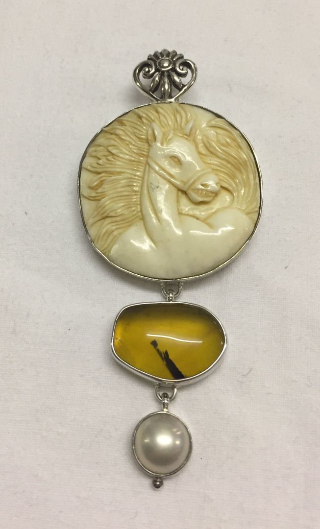 A carved horse head pendant/brooch set with a yellow opal cabouchon & a pearl in 925 silver.