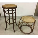 A tall cane stool with matching side table both with weaved cane tops.