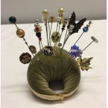 A collection of 22 vintage hat pins and stick pins on a cushion.