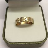 A 9ct gold wedding band decorated with hearts, size S. Total weight 2.4g.