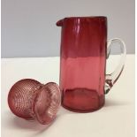 2 items of Cranberry glass. A small jug together with a salt, frill decoration to neck and spiral