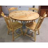 A round pine kitchen table with grey slate painted legs together with 4 pine kitchen chairs.