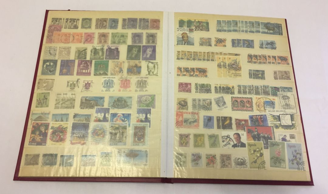 A maroon stamp album containing stamps from the Commonwealth.