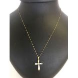 A 9ct gold cross set with clear stones on a 9ct gold chain.