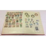 A red stamp album containing thematic stamps to include Sanda Island.