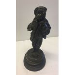 A spelter figurine of a boy begging with his dog, on a wooden plinth.