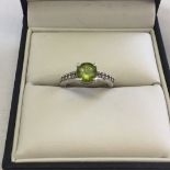 A 925 silver ladies ring set with a large central peridot and 5 cubic zirconias down each