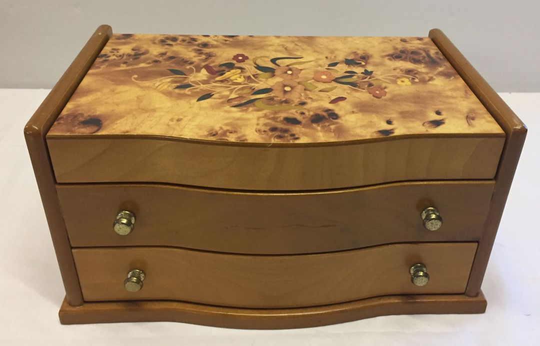 A light wood jewellery box with flower design to lid.