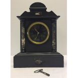 A black slate mantle clock with marble column detail. Approx 24 x 33cm - with key.