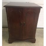 A small modern 2 door dark wood media cabinet with lift up lid.