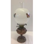 A copper and brass oil lamp with butterfly decoartion to glass shade.