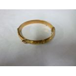 A 9ct gold oval bangle with engraved lea
