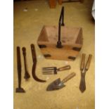 A selection of old gardening tools in a wooden basket.