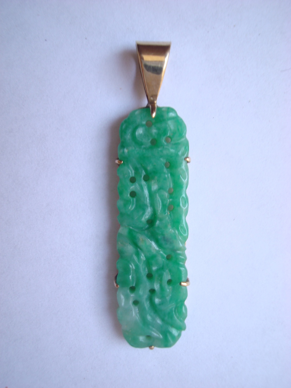 Yellow gold mounted carved and pierced jade pendant.