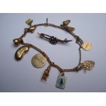 A 9ct charm bracelet with a late 19th Century 9ct brooch.