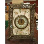 A 19th Century clock set into a tile mounted in a brass pierced frame.