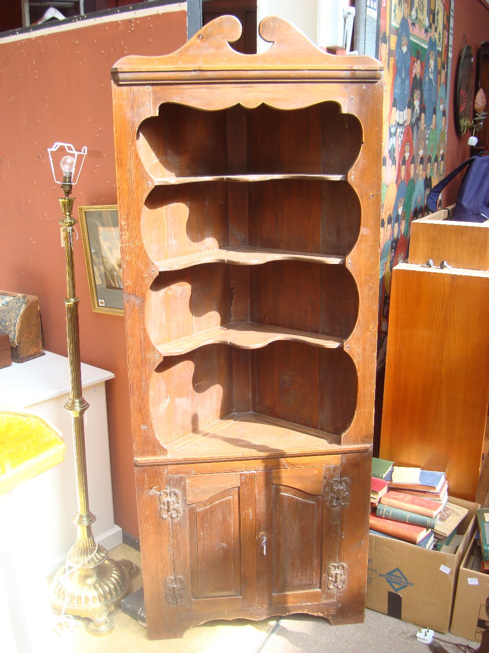 An early 20th Century stained pine standing corner cupboard,