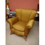 An early twentieth century upholstered armchair with outswept arms and scalloped back,