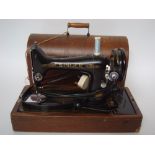 An early 20th Century Singer Sewing machine in walnut travel case fitted with electric motor.