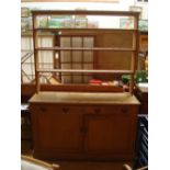 A pine dresser with plate rack, the body with two cupboards and two short drawers.