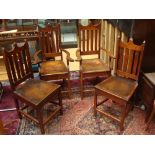 Four late 19th Century semi Gothic oak dining chairs.