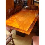 A modern burr walnut inlaid dining table on black lacquer square base.