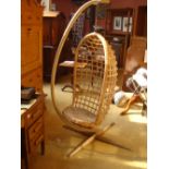 A mid-century wicker hanging chair with stand.