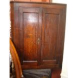 A George III oak hanging corner cupboard, with panelled doors enclosing shelves with shaped edges.