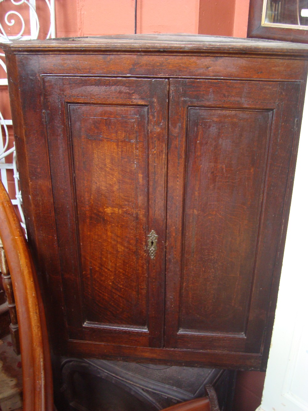 A George III oak hanging corner cupboard, with panelled doors enclosing shelves with shaped edges. - Image 2 of 2